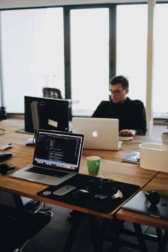 man-in-black-shirt-sits-behind-desk-with-computers-2102416 man-in-black-shirt-sits-behind-desk-with-computers-2102416